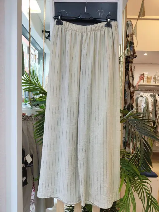 Conjunto dos piezas raya diplomatica compuesto por bluson de corte cuadrado con volante en la sisa y pantalon de goma elástica y pata ancha tipo palazzo. Para completar el look incluye un precioso colgante .