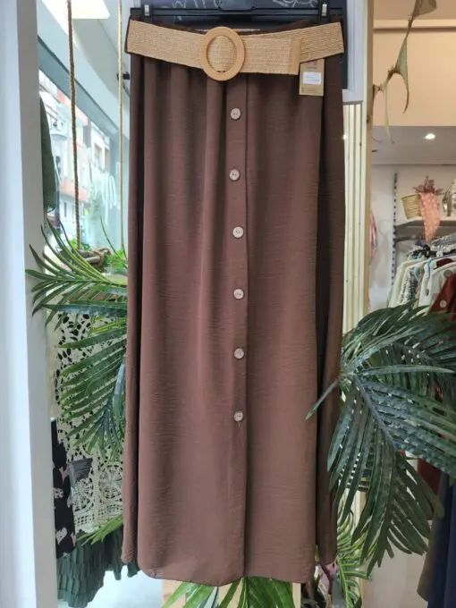 Falda botones marron. Falda larga de estilo fresco y elegante, con botonadura frontal decorativa y cinturón de rafia con hebilla redonda que realza la cintura. Confeccionada en tejido fluido, ideal para el verano. Talla única, cómoda y versátil. Disponible en varios colores.