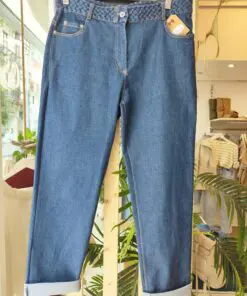 Denim RELAXED1. Pantalón vaquero azul medio con bajo vuelto y cinturón trenzado a juego. Corte recto y cómodo, ideal para looks diarios con un toque especial.