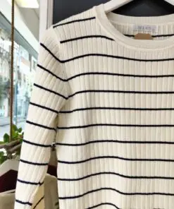 Jersey CANALE1. Jersey de punto canalé en color crudo con finas rayas horizontales en azul marino. Corte recto y cuello redondo, ideal para un look clásico con aire marinero. Su tejido elástico y suave lo convierte en una prenda cómoda y versátil para el día a día.