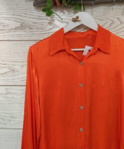 Detalle camisa de saten en color naranja.